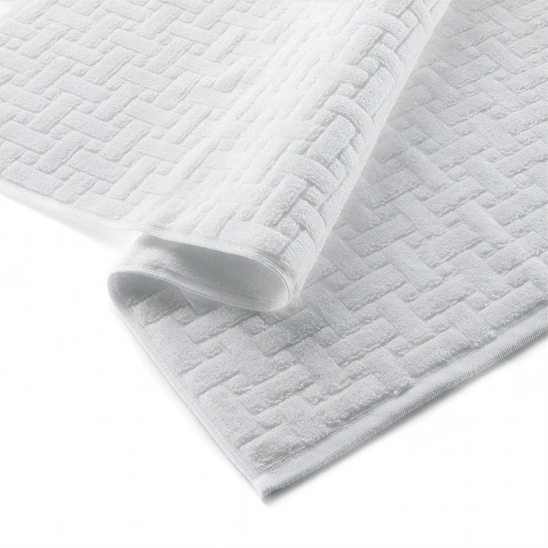 White product detail Glodina Embossed Bath Mat in White folded to show the raised geometric texture and finished edging